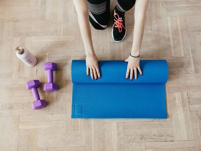 Sports mat and water bottle on a dark wooden floor.